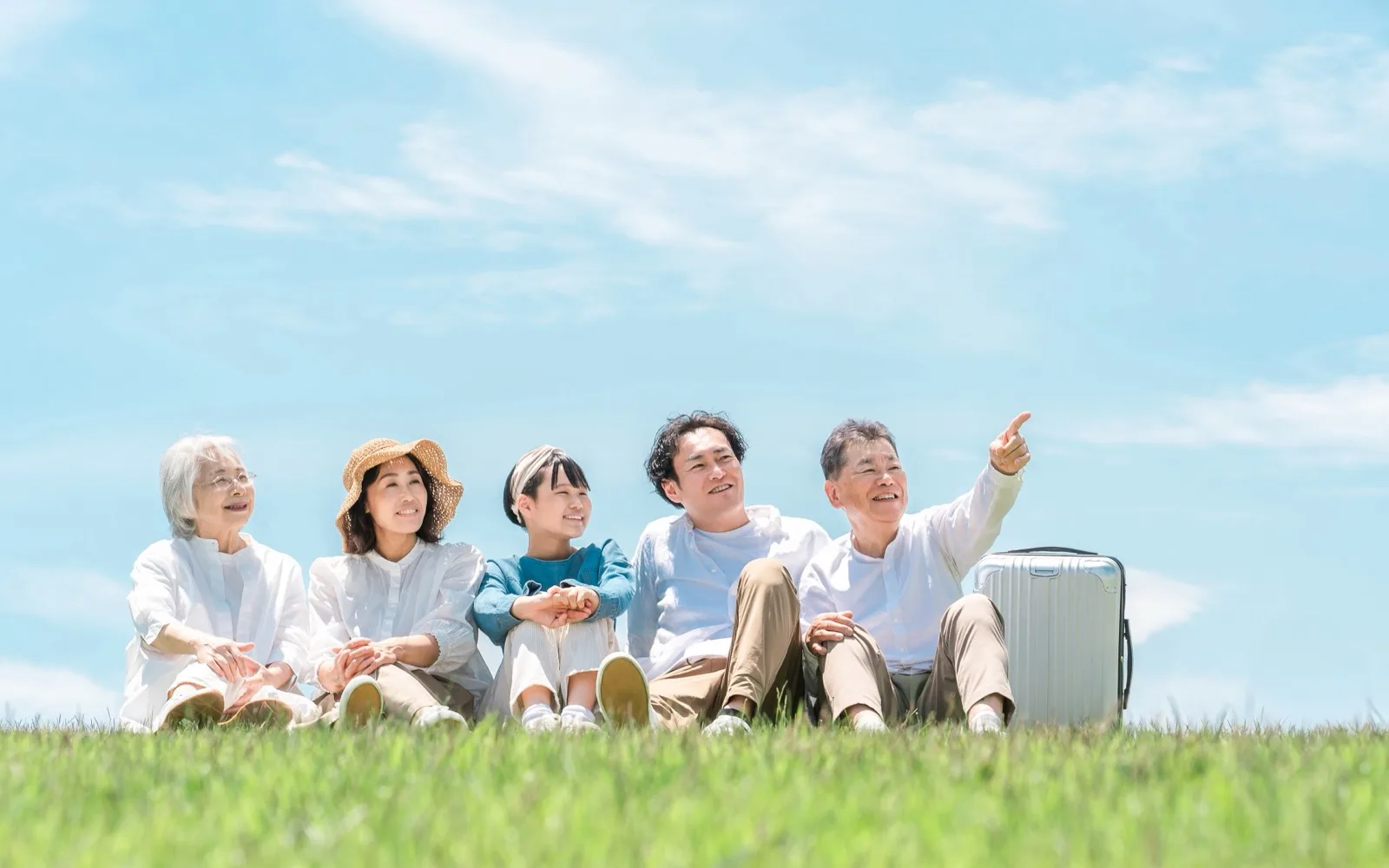 公園の丘に座って穏やかな時間を過ごす三世代家族